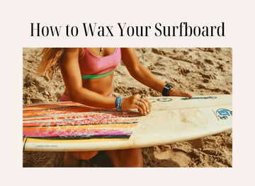 Woman waxing colorful surfboard on the beach, learning how to properly apply surf wax for better grip and performance.