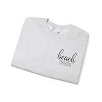 Beach Bum Ash Grey Crewneck Sweatshirt folded, featuring stylish text design on soft medium-heavy fabric. Perfect for beach lovers.