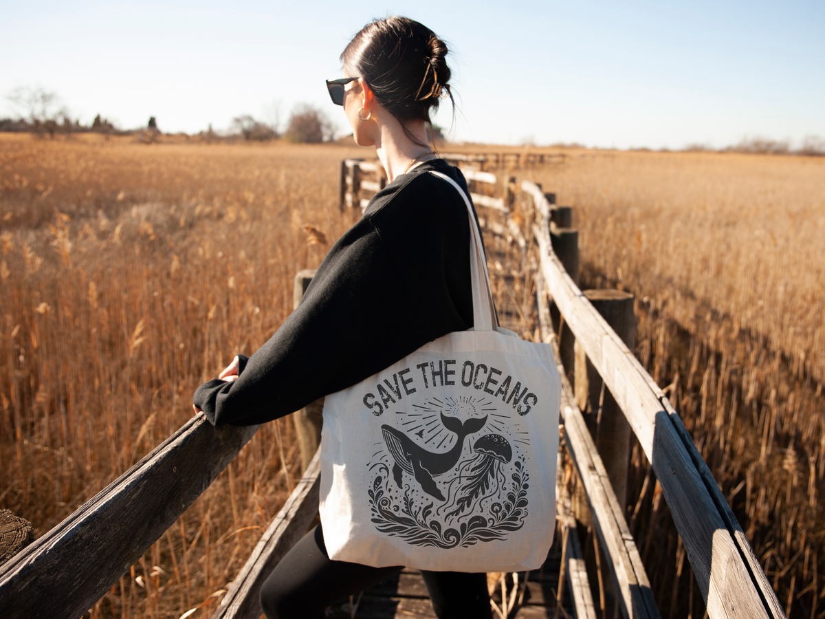 Woman carrying Save the Oceans Canvas Tote Bag on a wooden walkway in a natural setting