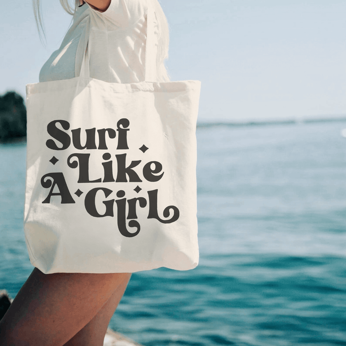 Surf Like a Girl Canvas Tote Bag by the beach, durable organic cotton tote with twin handles, perfect for beach essentials.